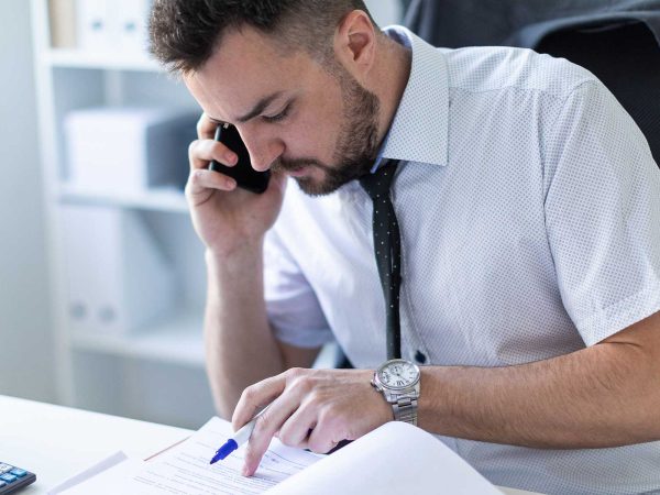 Man looking at a notebook while talking on the phone