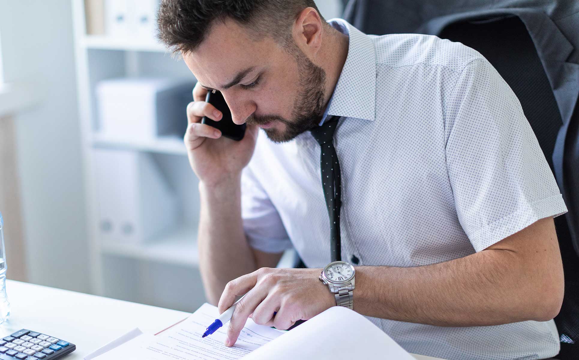 Man looking at a notebook while talking on the phone