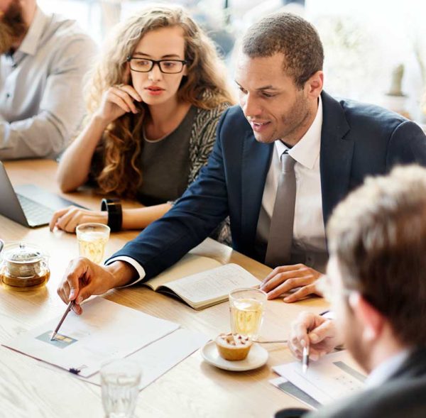 Group of people sitting together, discussing with a notebook.