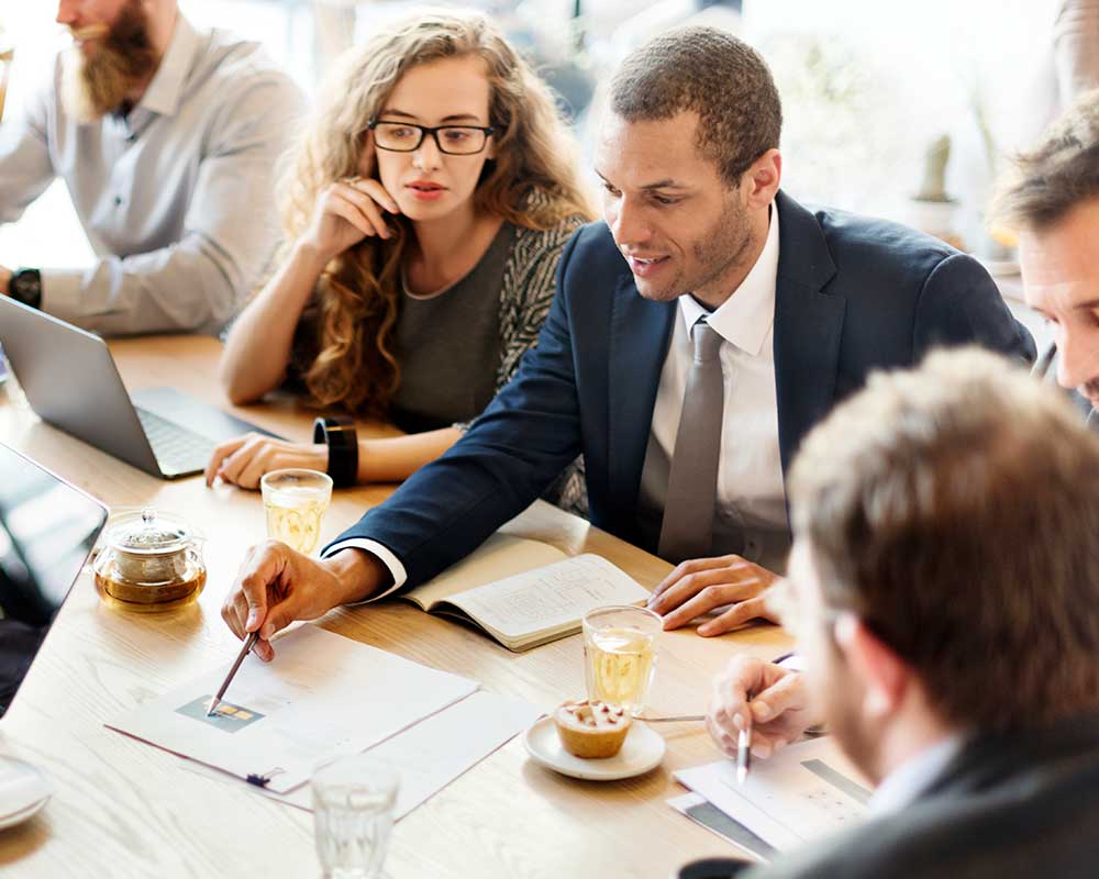 Group of people sitting together, discussing with a notebook.