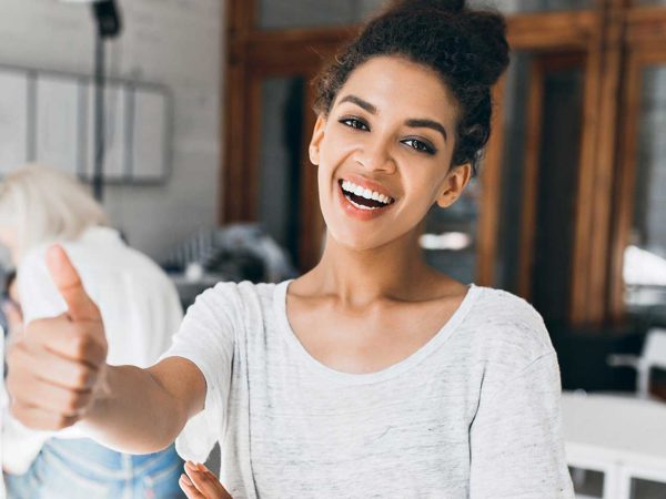 Woman smiling and giving a thumbs-up while speaking.