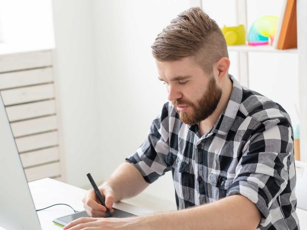 Man using a tablet while sitting in front of a laptop