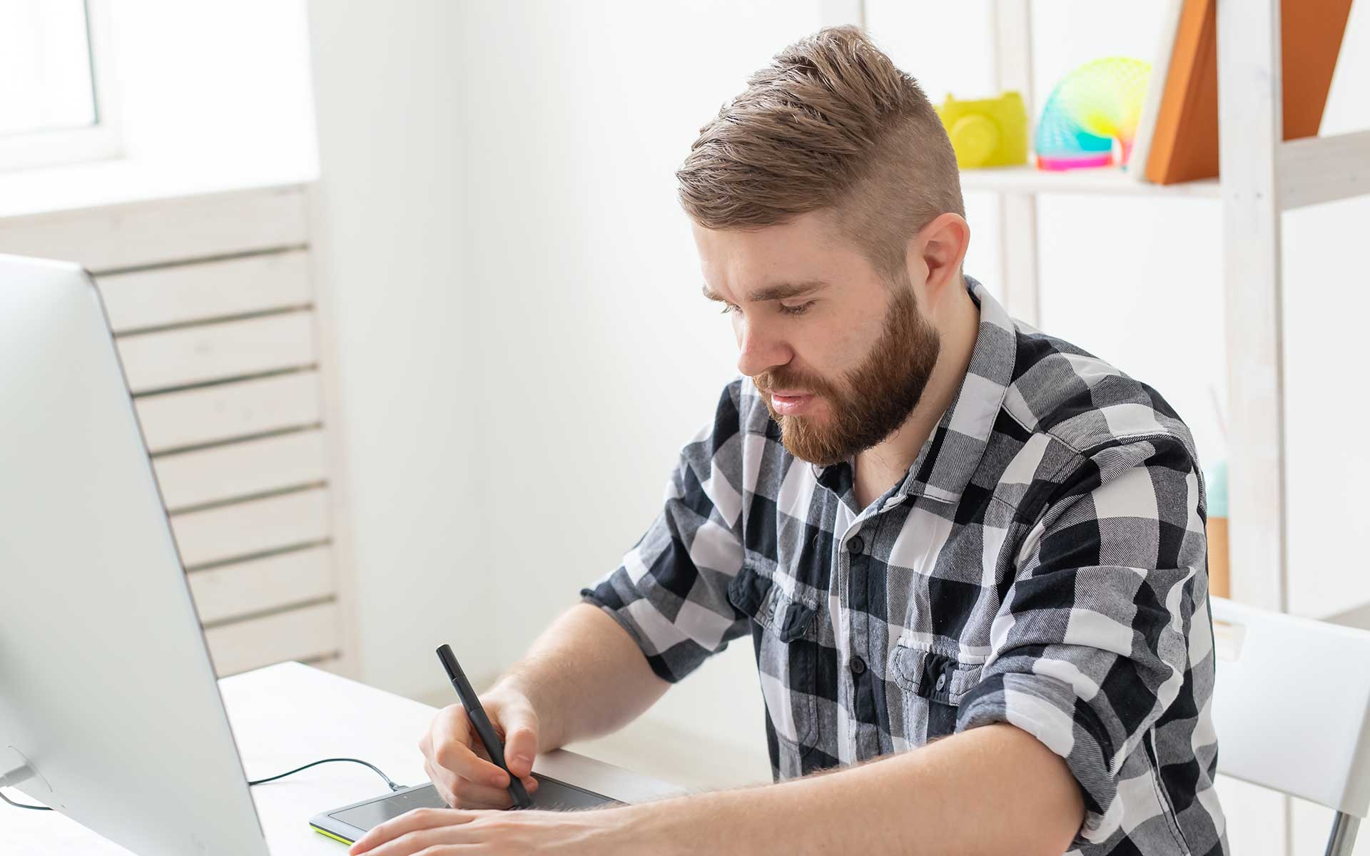 Man using a tablet while sitting in front of a laptop