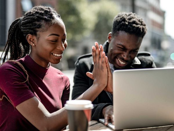 Man and woman using a laptop, smiling and giving a high five