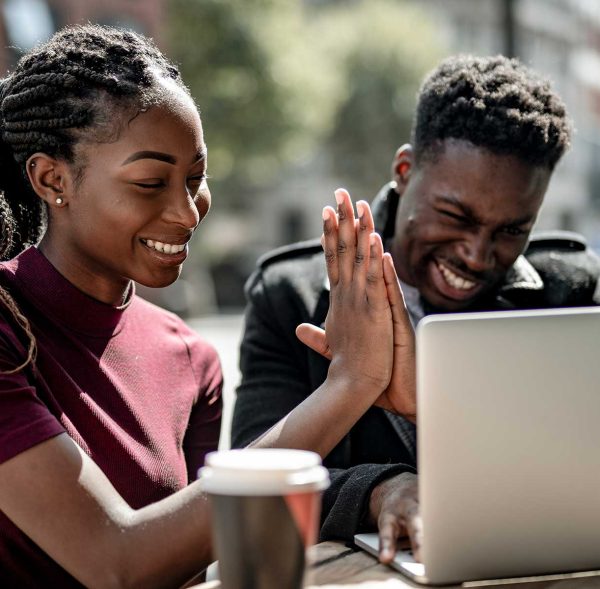 Man and woman using a laptop, smiling and giving a high five