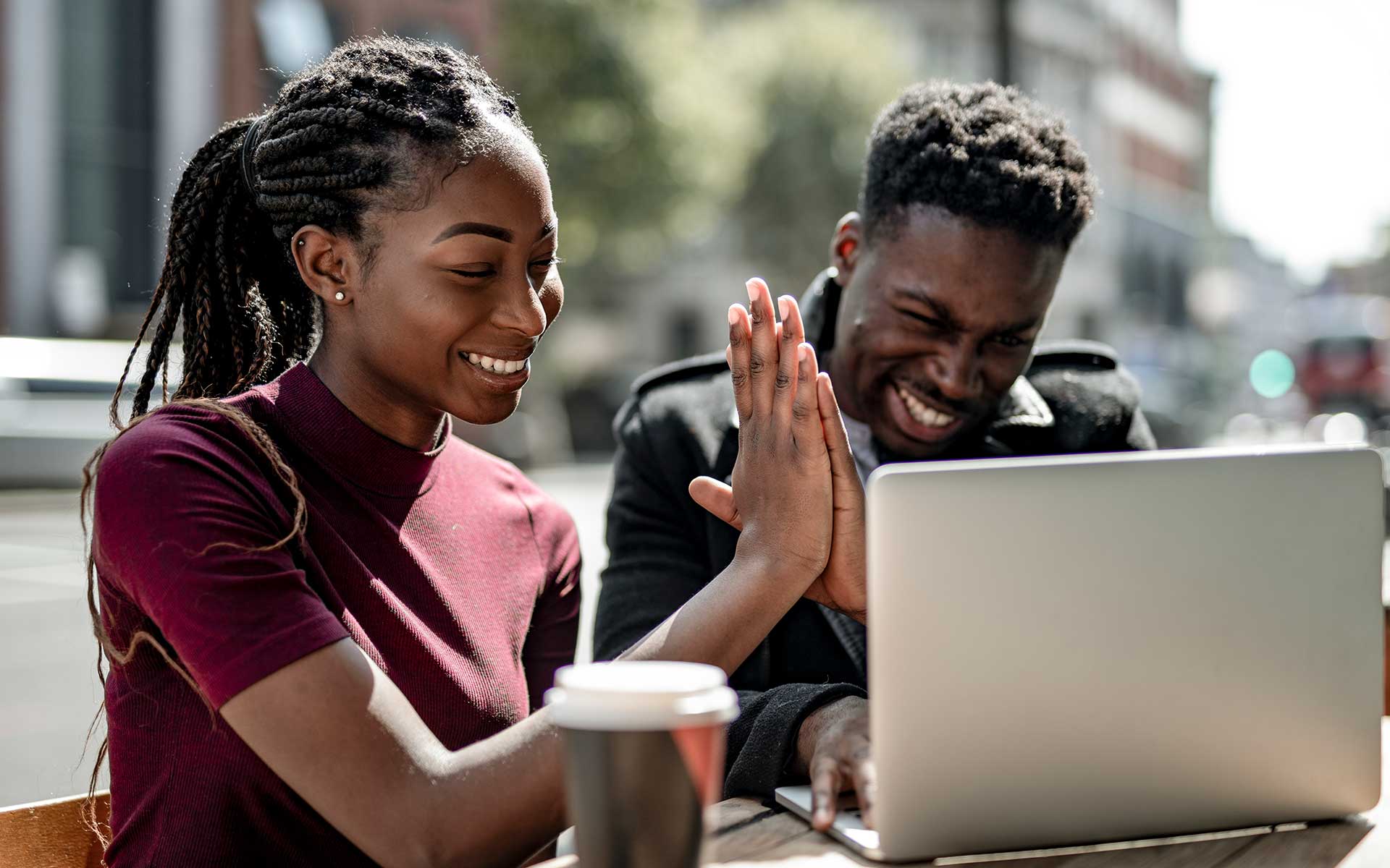 Man and woman using a laptop, smiling and giving a high five