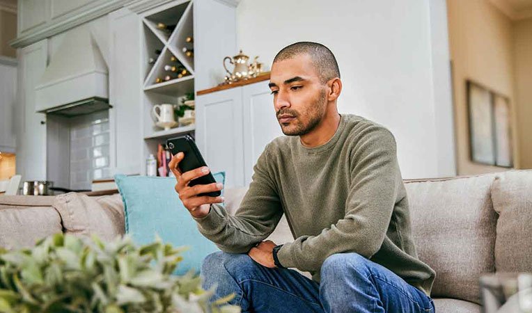 Man looking down while using a phone, symbolizing SLB-related depression
