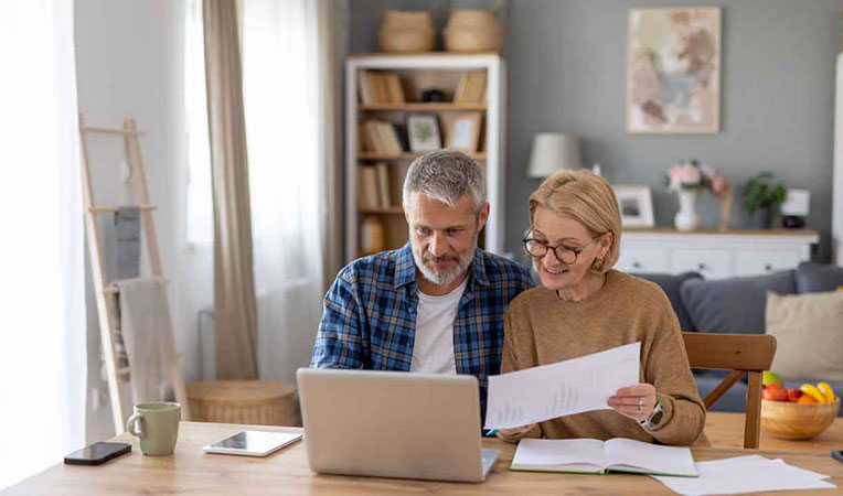 Man and woman using a laptop together while working on finance-related tasks