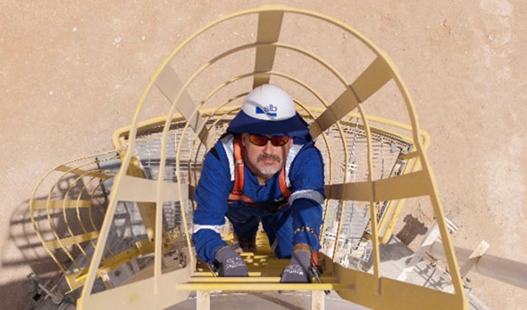 Man wearing blue attire and gown climbing, representing SLB insurances.