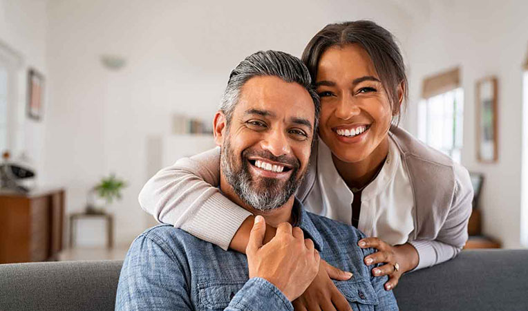 Happy woman placing her arm on a smiling man's shoulder, symbolizing coordination benefits