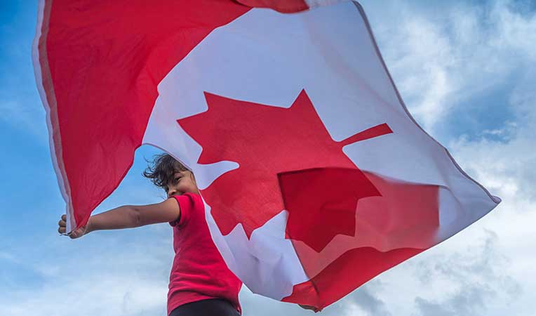 Child holding a Canadian flag, celebrating a national holiday
