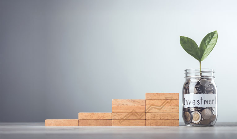 Glass jar filled with coins and a small plant growing from it, placed beside wooden blocks, symbolizing retirement products