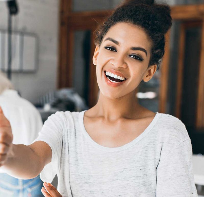 Woman smiling and giving a thumbs-up while speaking.