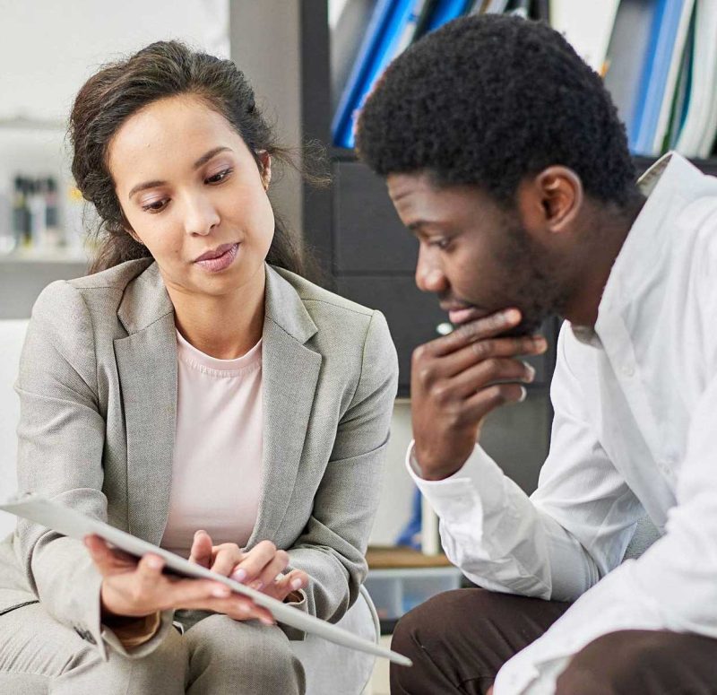 Woman showing something in a notebook to a man