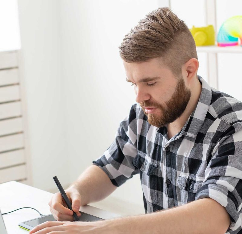 Man using a tablet while sitting in front of a laptop